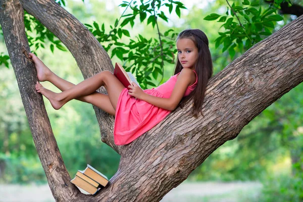 Okouzlující Holčička Dlouhými Hnědými Vlasy Čte Knihu Venkovní Posezení Stromě — Stock fotografie