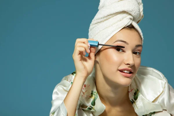 Jong Aantrekkelijk Vrouw Zetten Oog Mascara Blauwe Achtergrond Schoonheid Behandeling — Stockfoto