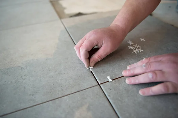 贴纸工把瓷砖铺在地板上 专业工人进行翻新 舵柄的手 住房翻新和建造新住房 — 图库照片
