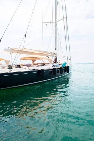 Ship\'s bow and aquamarine water in the port of Syracuse, Sicily. Boat and sea, detail. Sailing vessel drops anchor in a quiet bay