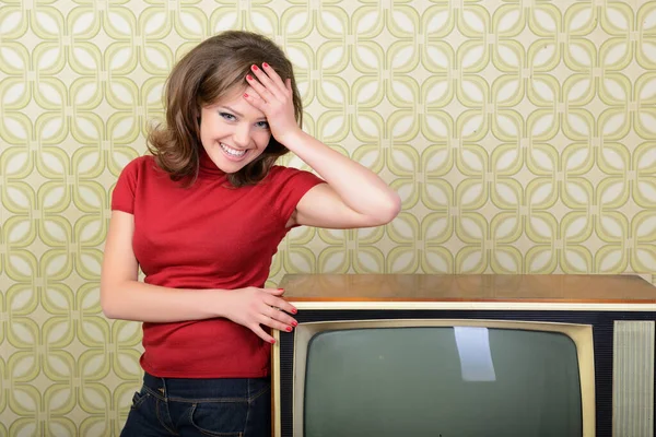 面带微笑的女人 带着老式墙纸和复古电视机 看着房间里的相机 复古风格化了60 70年代 — 图库照片