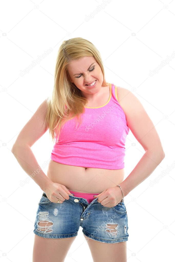 Obese woman is trying to close the buttons of her denim shorts, Readiness for summer. Overweight woman. Diet, fitness, excess weight, growing thin, sedentary life, balanced nutrition, overeating, cellulitis, problem of overweight concept. 