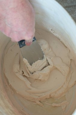 İşçi macunu yoğurur. Tamirci sıva tahtasıyla çalışır, kuru taş duvar yapıştırır, ev dekorasyonu yapar. Evde tamirat yapan bir adam. Erkek elinde oyuncak bıçak.