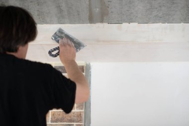 Hand work Worker putsty plasterboard ceiling in new appartment. Repairman works with plasterboard, plastering dry-stone wall, home improvement. Man makes repairs at house. 