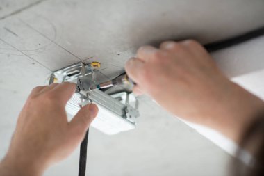 Adam lamba için tavana ipotek yaptırıyor. Tornavidayla erkek eli. DIY ev tamiri. Usta yeni binada tamirat yapıyor.