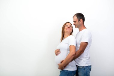 Hamilelik. Mutlu Aile Bebek Bekliyor. Adam koca göbekli hamile bir kadına sarılıyor. Karı ve kocanın kapalı bir portresi. Çift yaşam tarzı