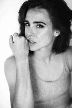 Çilli, güzel, genç, kızıl bir kadın. Evde poz veren, kameraya bakan, gündelik kıyafetler giyen çekici bir kızın siyah beyaz portresi.