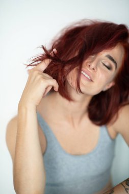 Güzel, genç, kızıl kadın. Evde poz veren, sıradan kıyafetler giyen çekici bir kızın portresi.