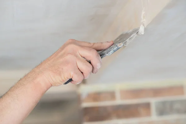 新大楼的工人用灰泥铺成的天花板 修理工与石膏板一起工作 在干石墙上涂石灰 改善房屋 一个人在家里修理 男方手拿着小刀 — 图库照片