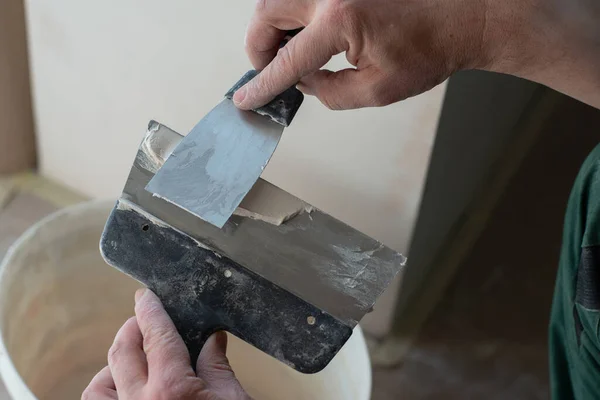 新大楼的工人用灰泥铺成的天花板 修理工与石膏板一起工作 在干石墙上涂石灰 改善房屋 一个人在家里修理 男方手拿着小刀 — 图库照片