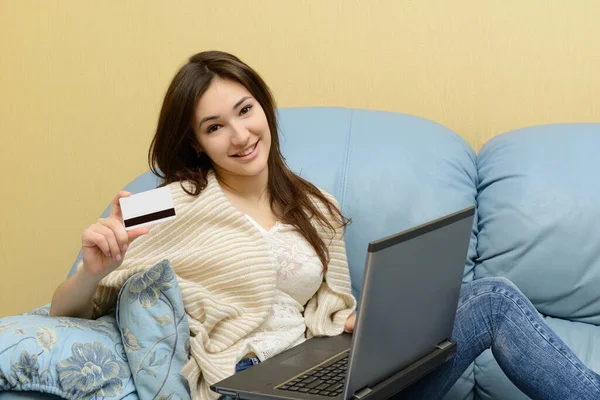 微笑的年轻女子坐在沙发上 用笔记本电脑和信用卡在网上购物 — 图库照片