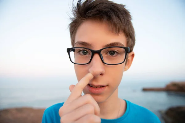 Muchacho Divertido Metiendo Dedo Nariz Piensa Algo Mirando Cámara Playa — Foto de Stock