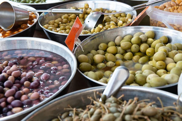 Different pickled olives in brine in outdoor market. Traditional spanish food. Snack