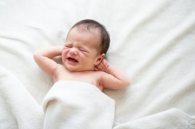 Yeni doğmuş bebek yatakta ağlıyor.