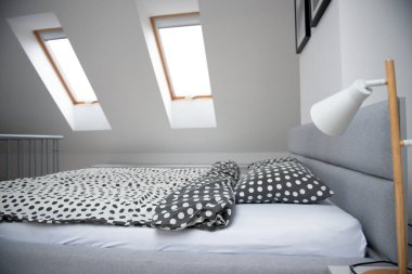 Modern monokrom tasarımı. Mansard 'da yatak odasının iç dekorasyonu. Ahşap yatak ve zarif aksesuarlar.. 