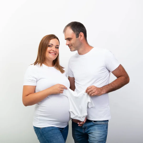Happy Family Expecting Bebé Mostrar Ropa Del Futuro Niño Que — Foto de Stock
