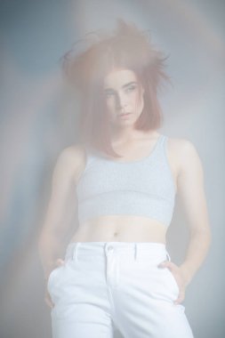 Güzel, genç, şık, kızıl bir kadın. Günlük kıyafetler giyip evde poz veriyor.. 