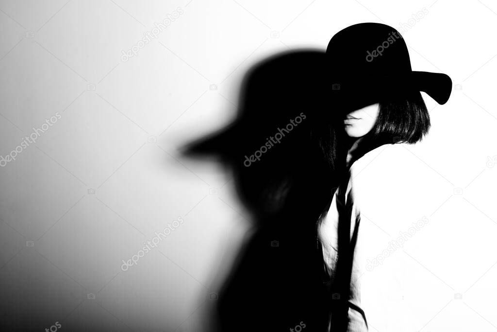 Mysterious fashion young woman in black hat and white shirt, copy space where can the advertising message be written, black and white