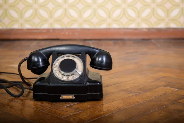 Telefone Preto Retro Está Chão Parquete Contra Papel Parede Vintage — Fotografia de Stock