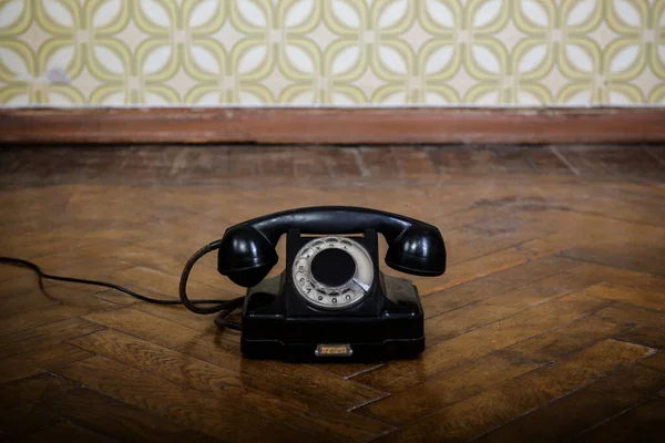 Telefone Preto Retro Está Chão Parquete Contra Papel Parede Vintage — Fotografia de Stock