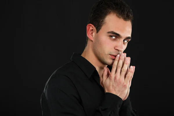 Hombre de camisa negra sosteniendo la mano cerca de la cara — Foto de Stock