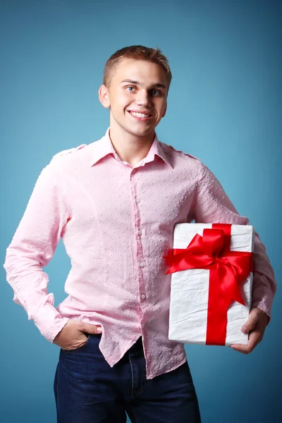 Рождественский мальчик держит подарочную коробку с красным бантом — стоковое фото