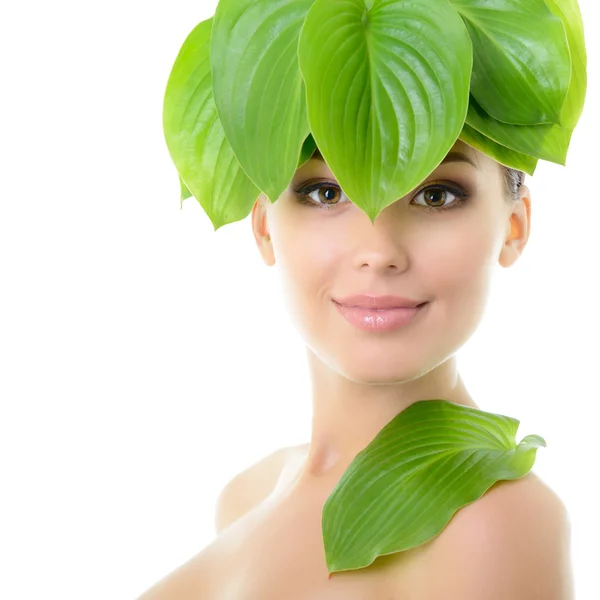 Vrouw met groene bladeren in de buurt van gezicht — Stockfoto