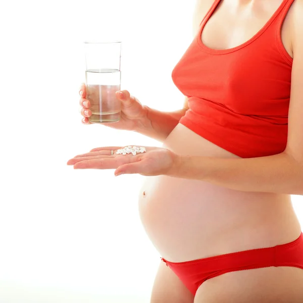 Mulher grávida com água e comprimidos — Fotografia de Stock