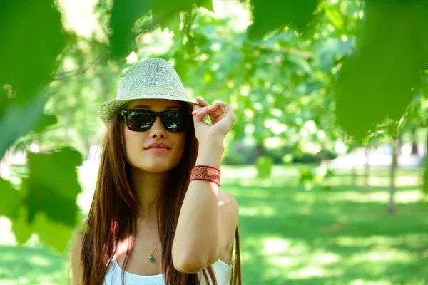 Mulher em óculos de sol e fedora no parque — Fotografia de Stock