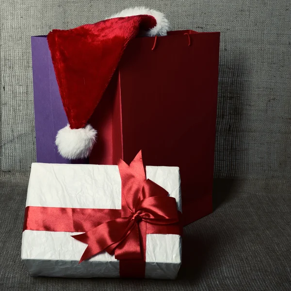 Christmas gift with shopping bags and Santa's hat — Stock Photo, Image