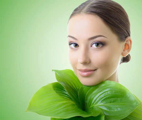 Frau mit grünen Blättern nahe ihrem Gesicht, — Stockfoto