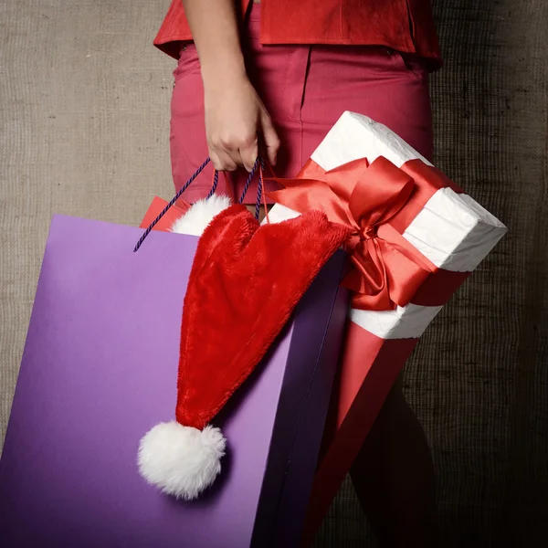 Mulher com presente, chapéu de Papai Noel e sacos de compras — Fotografia de Stock