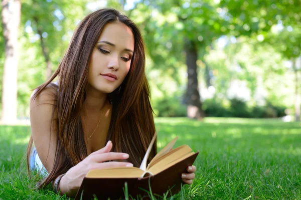 Jong meisje leesboek in park — Stockfoto