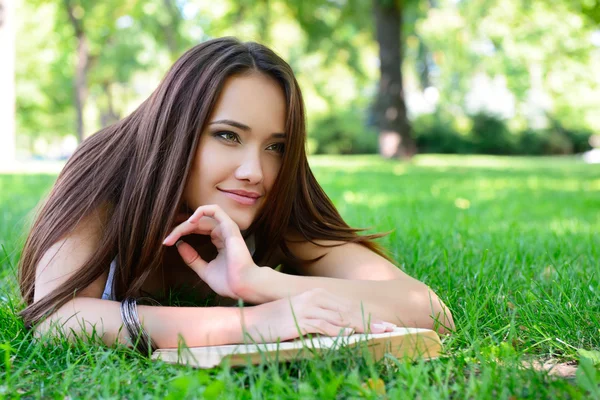 Fille couché sur l'herbe avec livre — Photo