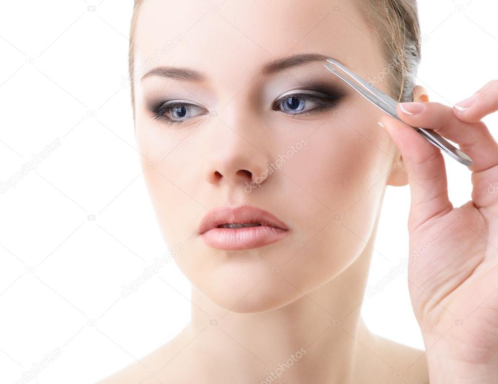 Beautiful girl plucking eyebrows