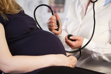 Pregnant woman having her blood pressure checked clipart