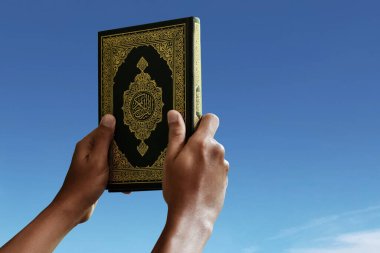 Religious muslim man holding holy quran clipart