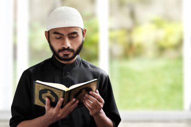 Religious asian muslim man reading quran clipart