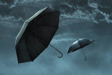 İki siyah şemsiye gökyüzünde uçuyor, sağanak yağmur kara bulutlu fırtına