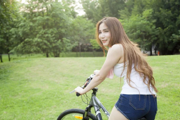 Γυναίκα ιππασίας ένα ποδήλατο γυμναστικής στο πάρκο. — Φωτογραφία Αρχείου