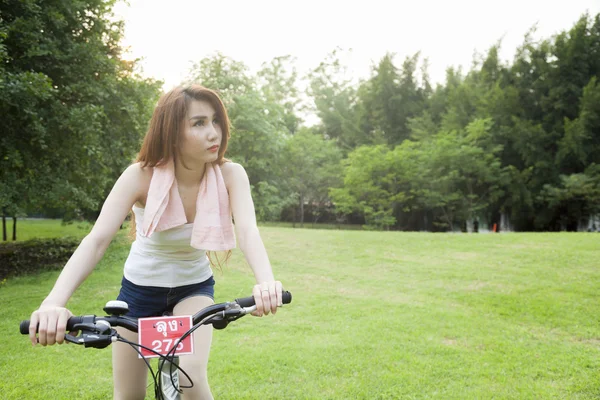 Mulher montando uma bicicleta de exercício no parque . — Fotografia de Stock