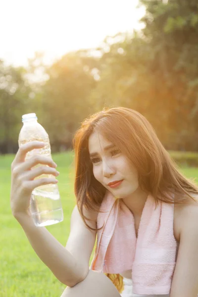 Donna seduta e con in mano una bottiglia d'acqua . — Foto Stock