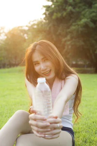 Mujer sosteniendo una botella de agua y la entregó a . — Foto de Stock
