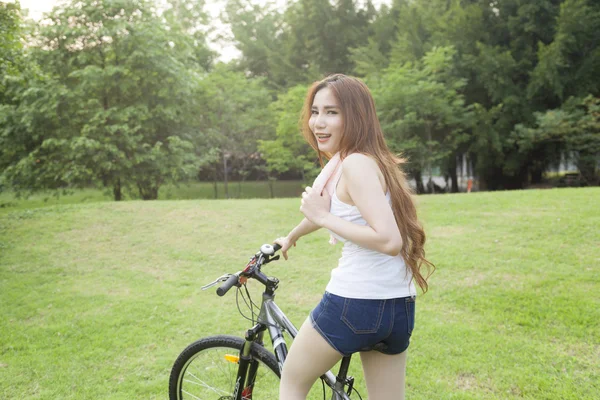 Mulher montando uma bicicleta de exercício no parque . — Fotografia de Stock