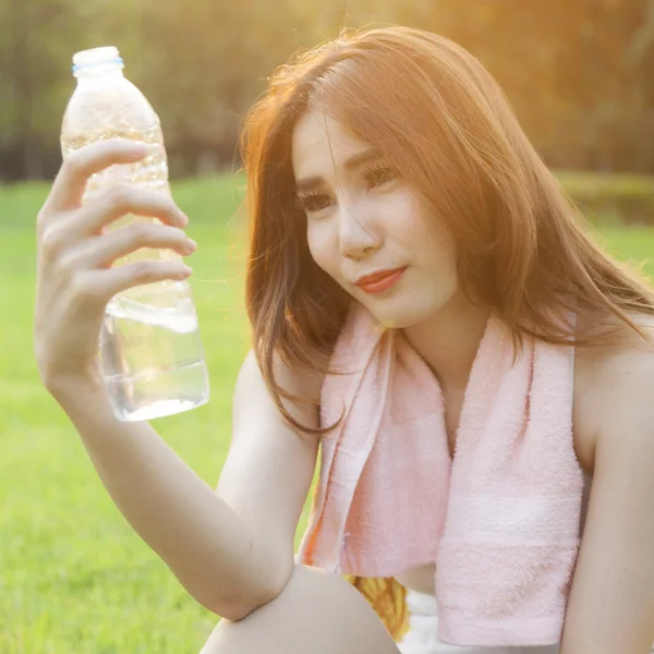 Vrouw zitten en houden een fles water. — Stockfoto