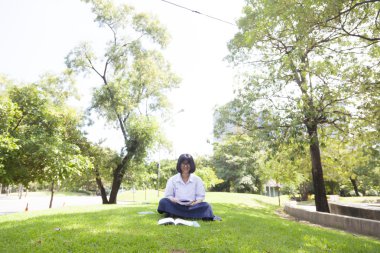 Çimenlerin üzerine oturmuş öğrenci ödev.