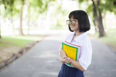Liseli kız ayakta tutan bir kitap.