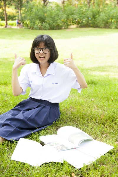 Schulmädchen lächelt und sitzt Hausaufgaben. — Stockfoto