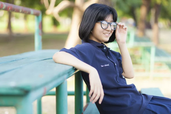 Ragazza con gli occhiali seduta sulla panchina . — Foto Stock