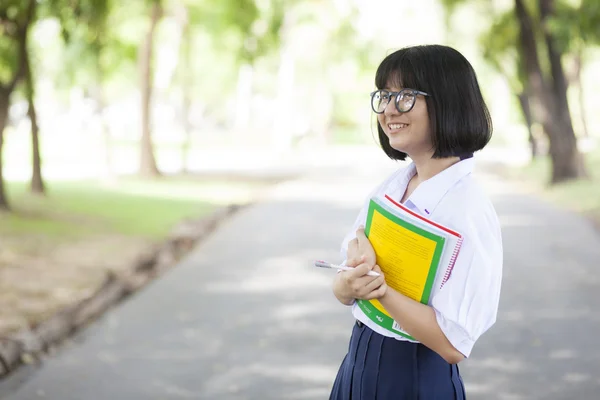 Schoolgirl standing holding a book. — Stock Photo, Image